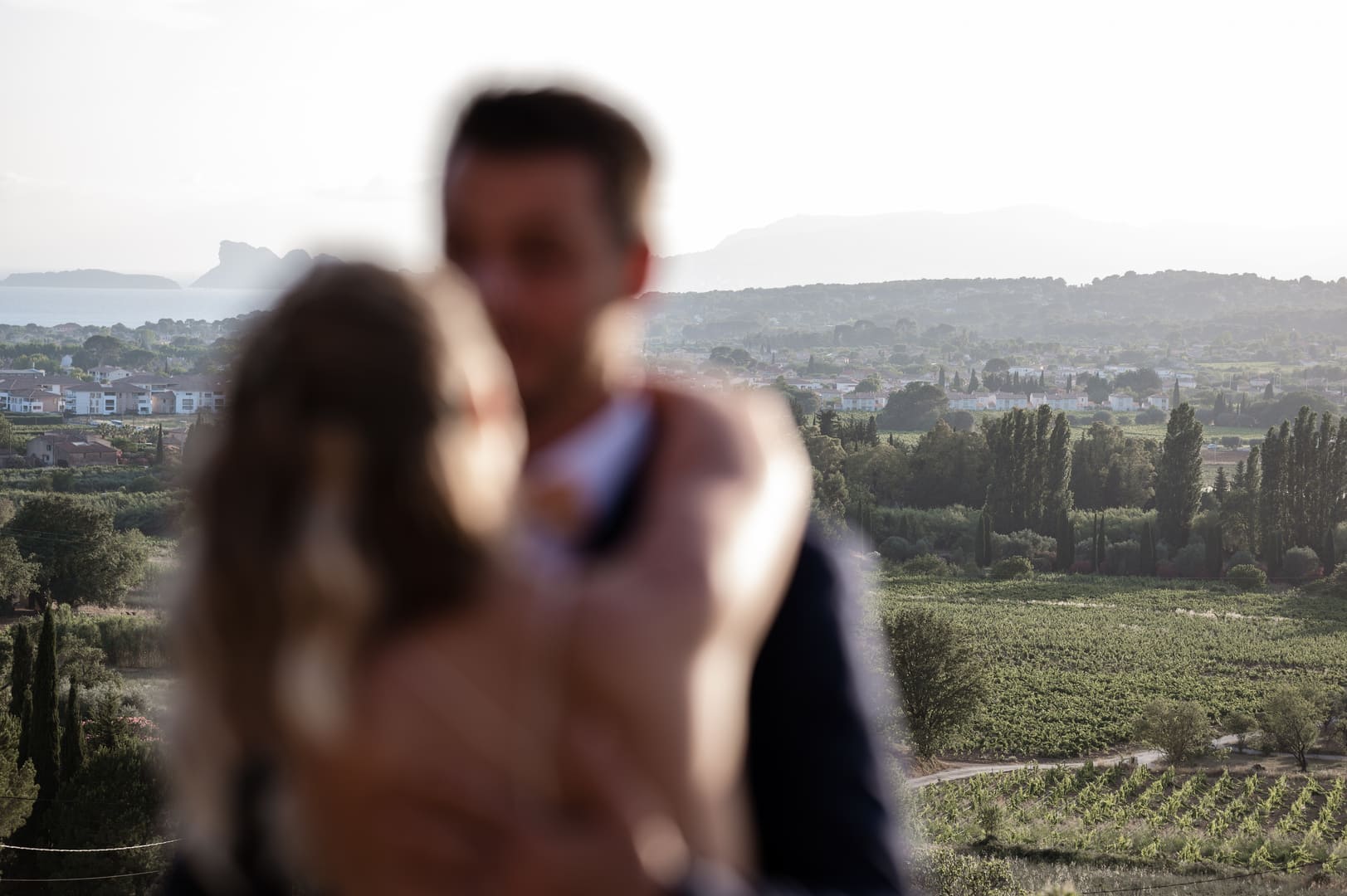 les mariés s'embrassent avec une vue provençale derrière eux