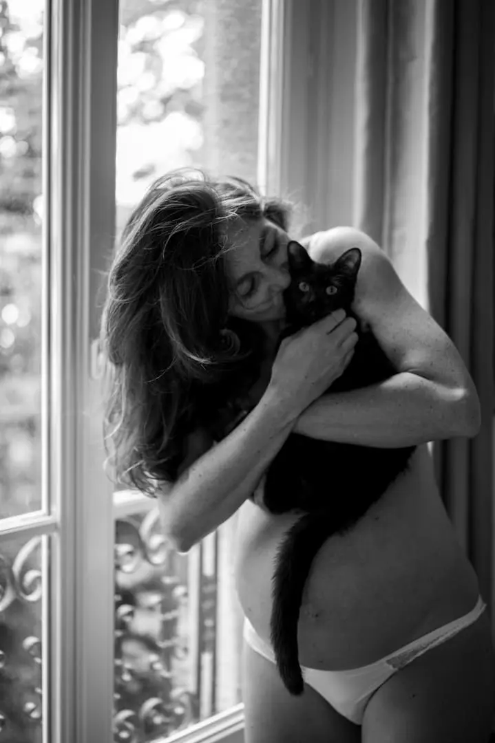 femme enceinte au naturel en sous-vêtements à sa fenêtre avec son chat