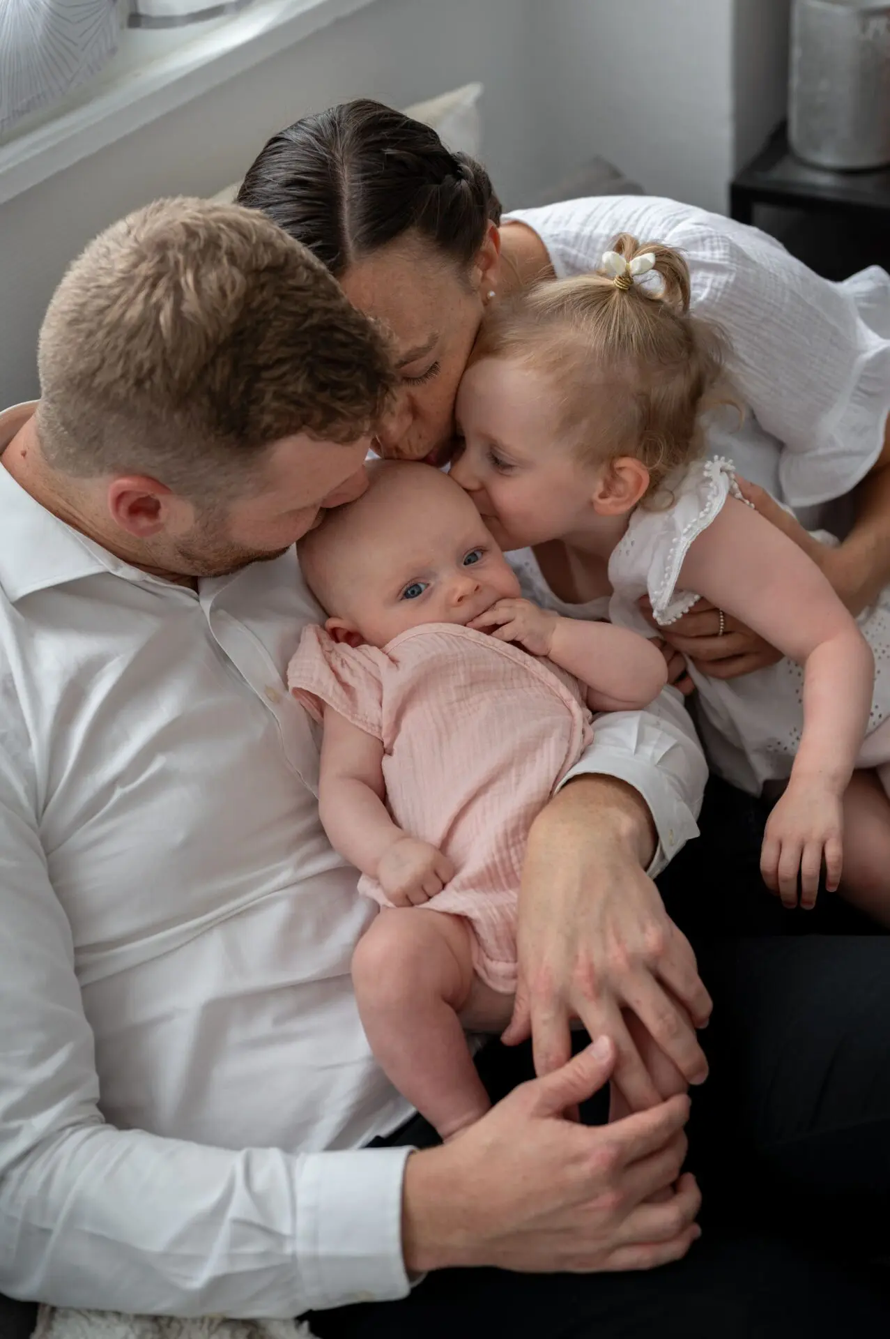 famille au complet embrasse la nouvelle petite soeur sur le canapé