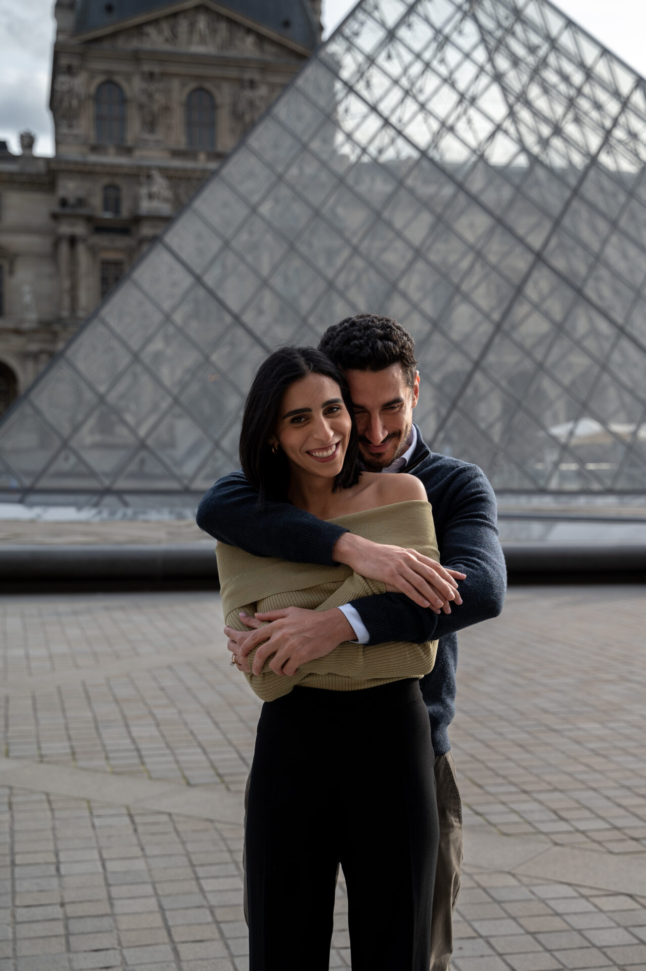 couple américano-égyptien fraîchement fiancés s'enlace place du louvre