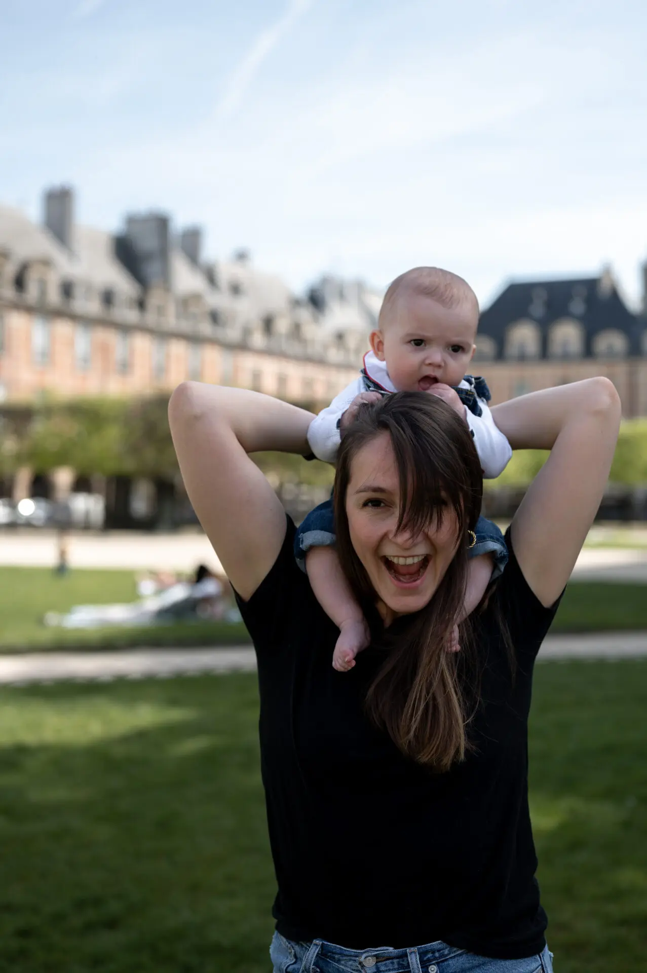 une mère porte son bébé sur les épaules et crie de bonheur