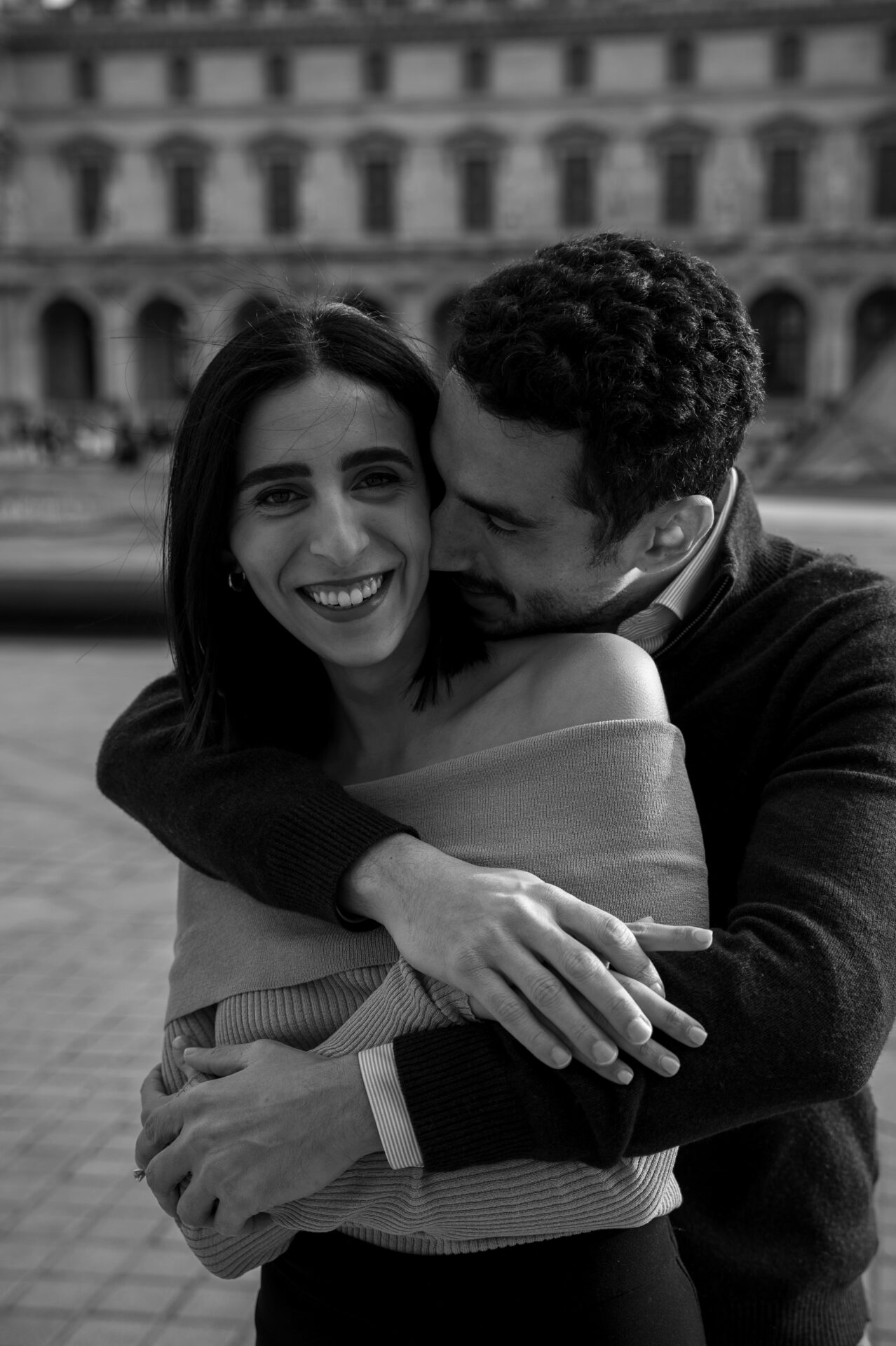 jeunes fiancés s'enlacent sur la place du louvre à Paris