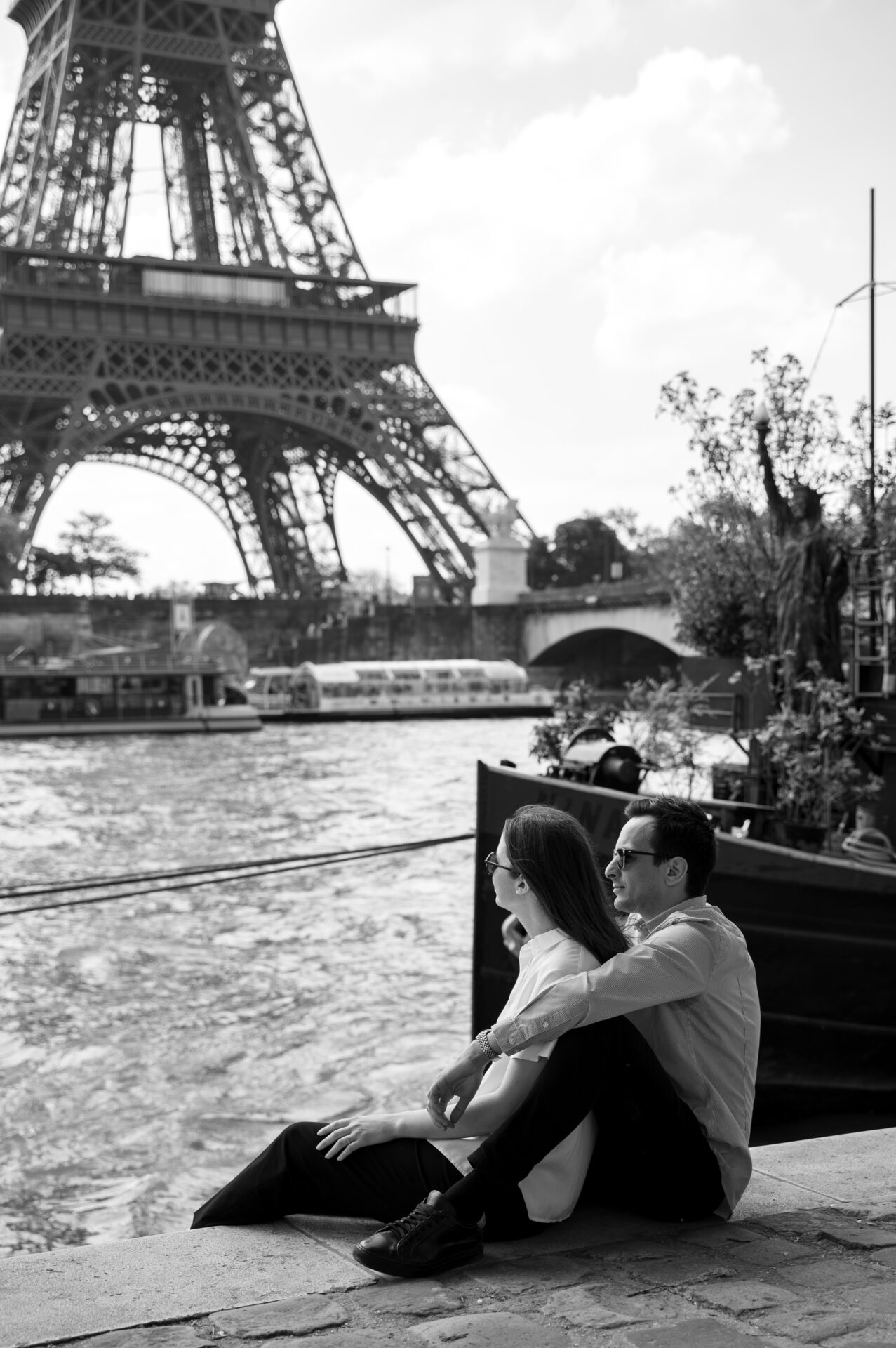 couple fiancé assis sur les quais de seine devant la Tour Eiffel