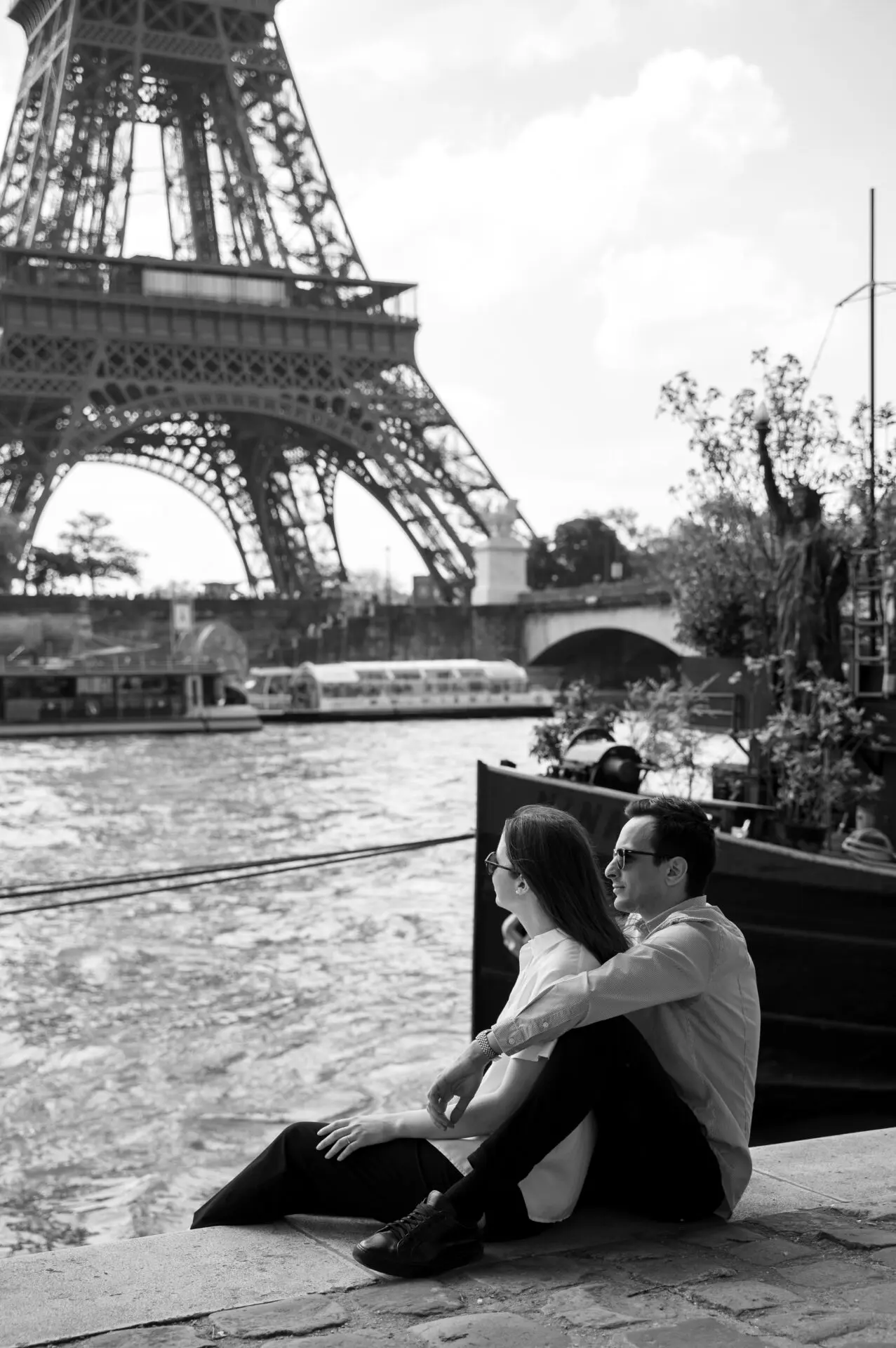 couple fiancé assis sur les quais de seine devant la Tour Eiffel