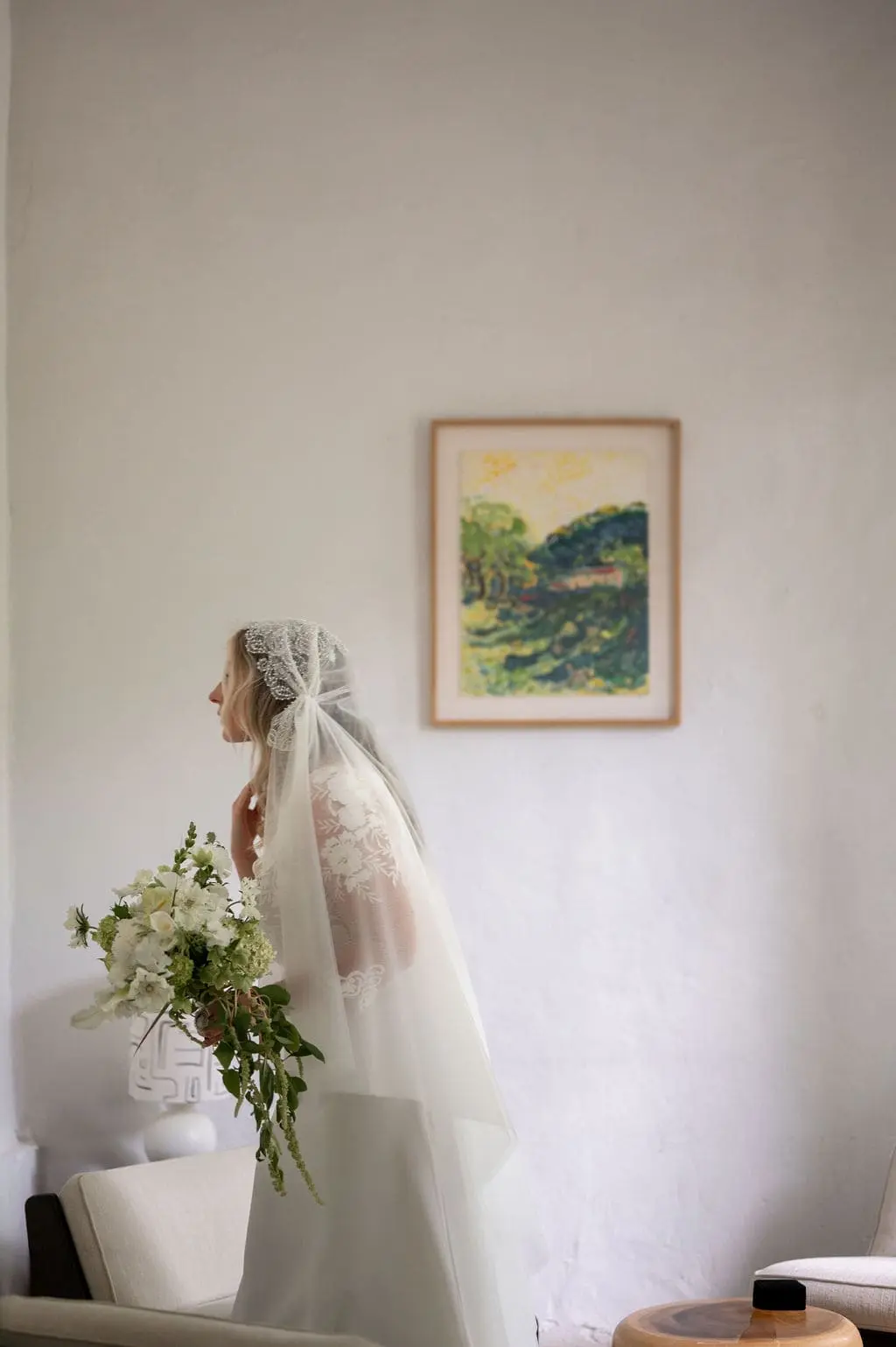 bride fixing her hair in front of a mirror with her bouquet