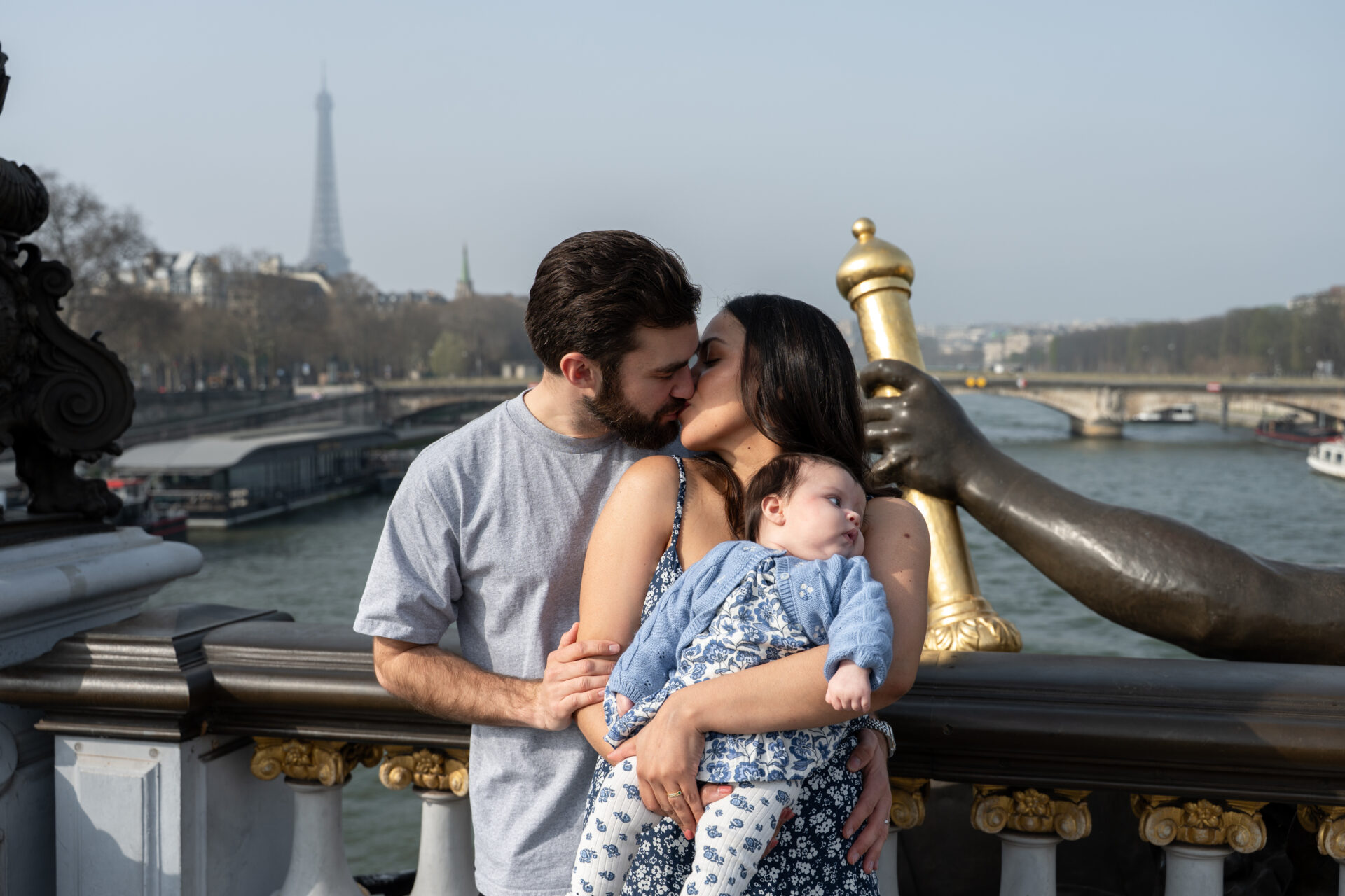 couple de jeunes parents avec leur bébé et la tour eiffel en fond